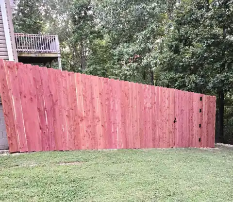 8-foot cedar privacy fence running along a sloped back lawn