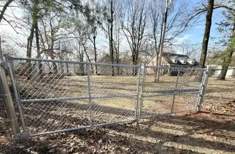 Galvanized chain link drive gate in a wooded lot