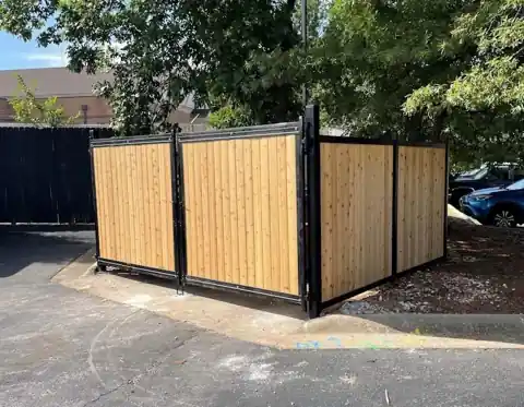 Cedar infill panels in black steel frames forming a dumpster enclosure