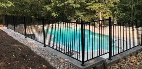 Black iron pool fence on a block wall around a new pool