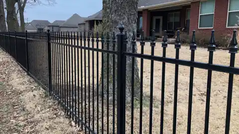 Spear-top black iron fence across a front yard in Rogers