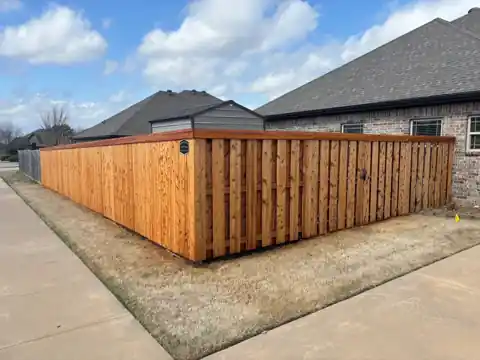 Stained cedar board-on-board fence run along a sidewalk, finished by Local Stain