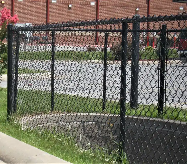 Black vinyl-coated chain link fence around a commercial drainage area