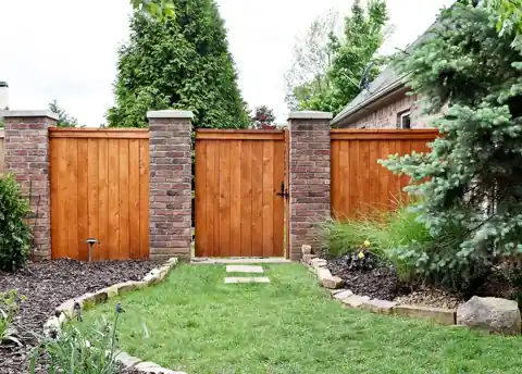 Cedar gates set between brick columns over a lawn path, built on site by Privacy Fence