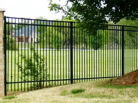 Tall black iron fence running along a slope