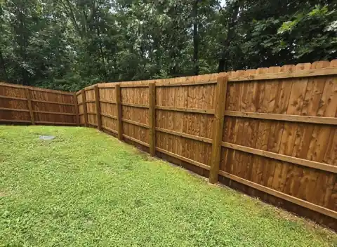 Stained cedar privacy fence along a back lawn