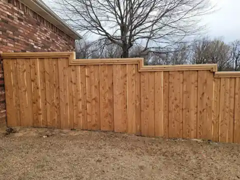 Stepped cedar privacy fence running along the side of a brick house